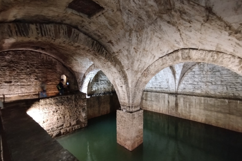 Fontana del Lantro a Bergamo Alta, antica cisterna sotterranea con volte a crociera in pietra, pilastri e acqua illuminata.